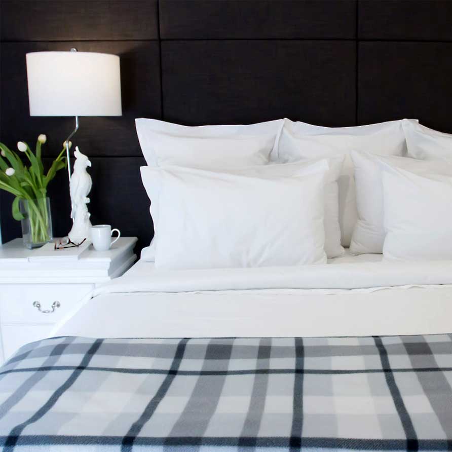Bed with collection of pillows and bedside lamp in the Parkside Suite